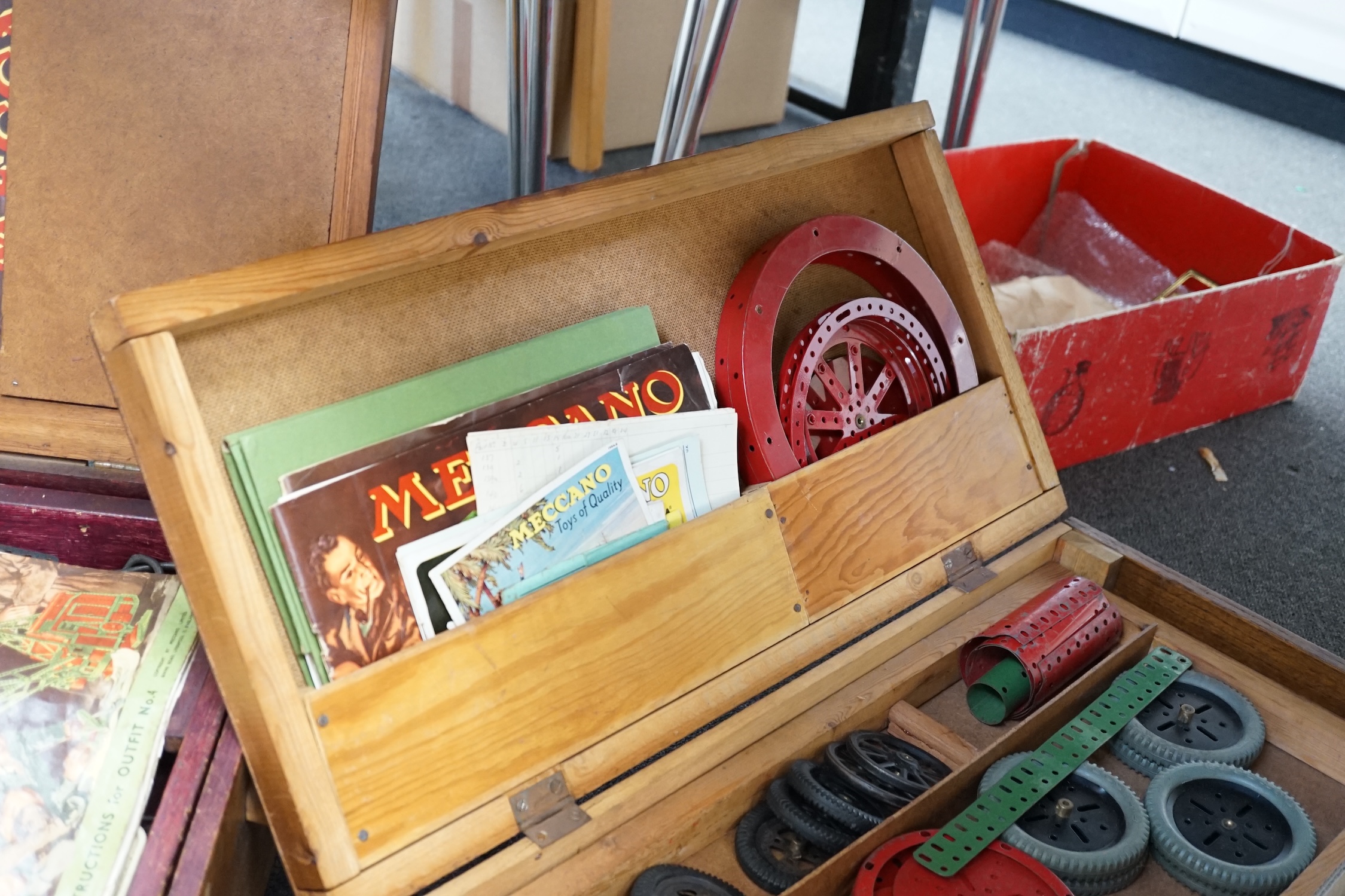 A collection of early Meccano components, mainly from the red and green period, comprising of some of the more unusual wheels and circular parts, some instruction books, etc. well organised into two wooden boxes